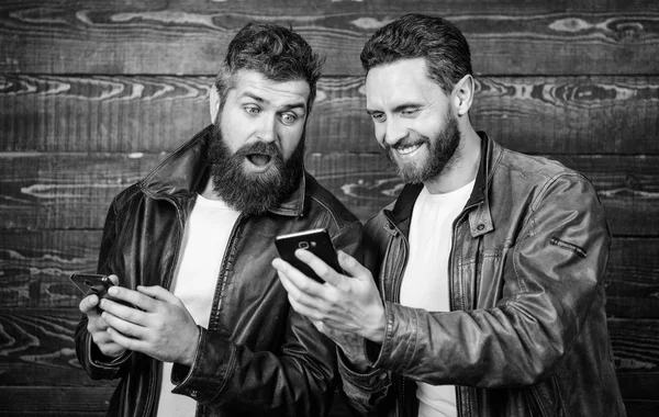 Online bedrijf. Moderne technologie. Mannen met smartphones surfen op internet. Mobiel internet. Bedrijfstoepassing. Mannen brute bebaarde hipster in modieuze lederen jassen gebruiken mobiel internet — Stockfoto