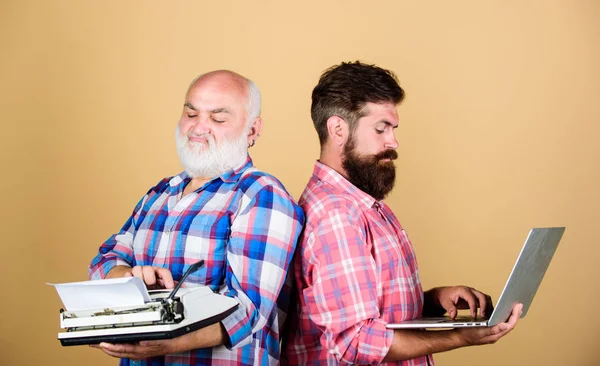 two bearded men. Vintage typewriter. technology generation battle. Modern life. father and son. technology development and improvement. retro typewriter vs laptop. youth vs old age. business approach