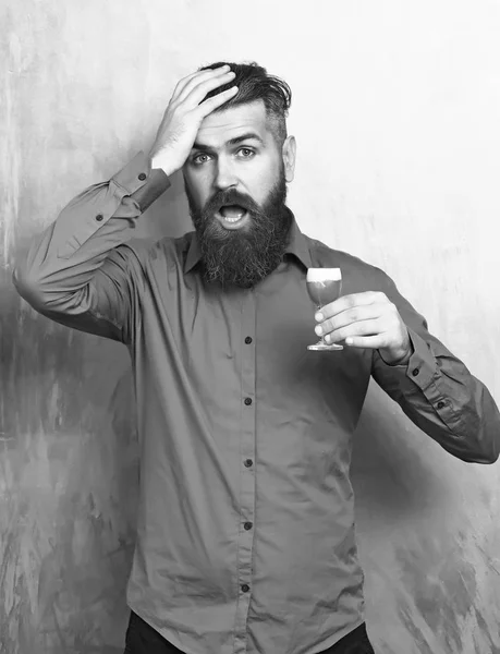 Brodaty mężczyzna, długą brodę. Brutalne kaukaski hipster zaskoczony z wąsami w brązowy shirt trzymając alkoholowych strzał czerwony kolorowy tekstury tła — Zdjęcie stockowe