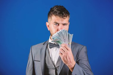 Resmi takım elbise mavi arka plan doları banknot yığını tutun. İşadamı nakit para var. Zenginlik ve refah kavramı. Nakit para kolay ve hızlı bir şekilde almak. Para gibi kokuyor. Kolay nakit krediler