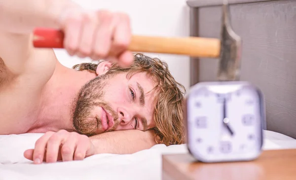 Un tipo tocando con un martillo sonando el despertador. Romper el régimen de disciplina. Un sonido molesto. Deja de sonar. Molesto despertador sonando. Hombre barbudo molesto cara somnolienta yacía almohada cerca del despertador —  Fotos de Stock