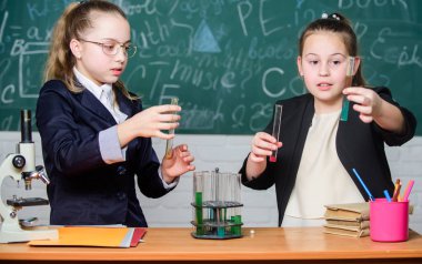 Kimyasal reaksiyonlar gerçekleştirin. Kimyanın temel bilgisi. Kız sınıf arkadaşları kimya okuyor. Kimya okumayı ilginç hale getir. Eğitici deney konsepti. Mikroskop ve test tüpleri masada