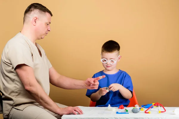 Egészségügyi. Orvosi vizsgálat. Fiú aranyos gyermek és apja orvosa. Kórházi munkás. Elsősegélynyújtás. Orvosi segítség. Trauma és injurie. Medicine koncepció. Kid kis orvos Sit asztal orvosi eszközök — Stock Fotó