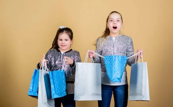 Meisjes zusters vrienden met shopping tassen beige achtergrond. Winkelen en kopen. Zwarte vrijdag. Verkoop en korting. Dagje winkelen. Kinderen houden boeket pakketten. Kinderen mode. Verwacht meer. Minder betalen — Stockfoto