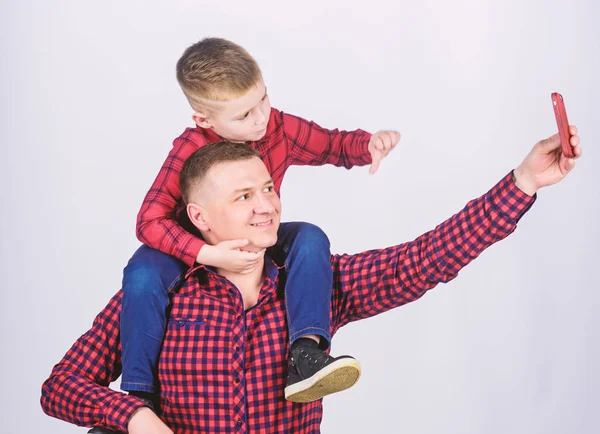 Oğluyla selfie çekmek. Babaların omuzlarına binen çocuk. Çocuğun babası olmanın mutluluğu. Eğleniyor. Babalar günü. Asil bir insanın baba örneği. Baba küçük oğlu kırmızı gömlek aile kıyafeti bakmak — Stok fotoğraf