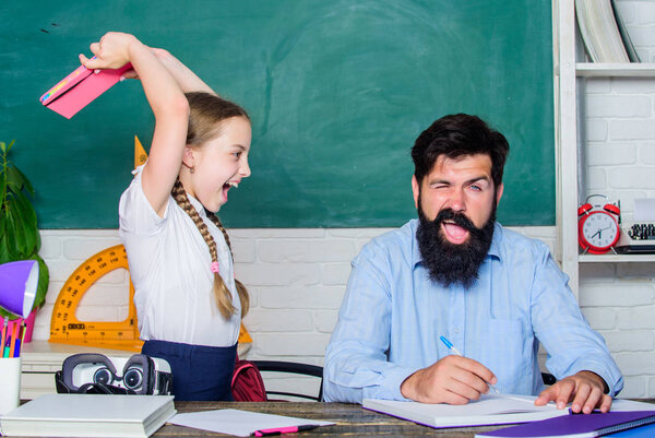 Angry girl hates reading book. back to school. Private teaching. small girl child with bearded teacher man in classroom. private lesson. knowledge day. Home schooling. daughter study with father