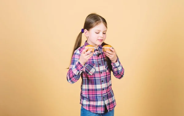 Μαγειρική φρεσκάδα κάθε μέρα. Το χαριτωμένο μικρό παιδί απολαμβάνει το ψήσιμο και τρώει γλυκό φαγητό. Αξιολάτρευτο κοριτσάκι που κρατούσε φρεσκοψημένα κεκάκια. Ακολουθώντας την καλύτερη συνταγή ψησίματος. Σπιτικό ψήσιμο — Φωτογραφία Αρχείου