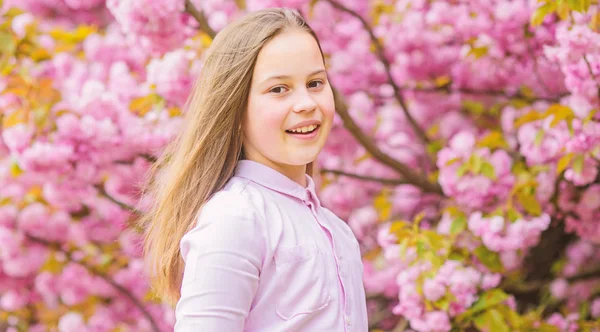 La niña disfruta de la primavera. Niño sobre flores rosadas de sakura fondo del árbol. Chico disfrutando de la flor de cerezo sakura. Feliz vacaciones de primavera. Primavera en el jardín botánico. Así huele la primavera. Flor tierna — Foto de Stock