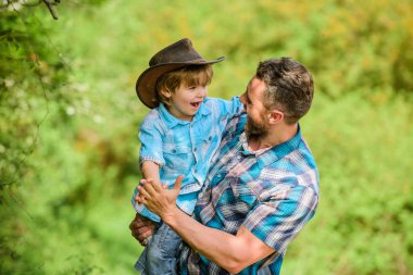 Rustik bir aile. Sevimli kovboy büyüyor. Bahçede küçük yardımcı. Küçük çocuk ve baba doğada arka planda. Maceraların ruhu. Baba gibi güçlüsün. Çocuk eğlenceli kovboy baba sahip. Güç baba olmak