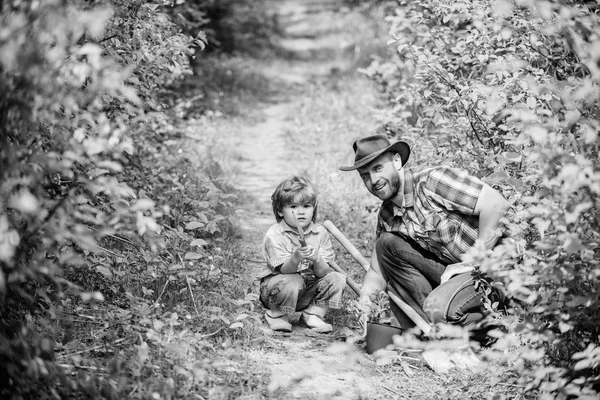 Farm family. Little boy and father in nature background. Gardening tools. Spring gardening routine. Planting flowers. Gardening hobby. Dad teaching little son care plants. Little helper in garden