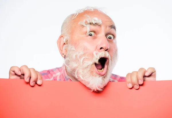 Folie des plumes. Homme barbu visage émotionnel mature avec des plumes blanches collées de près. Un drôle de pensionné qui devient fou. Concept de publicité. Une fête d'oreillers. Des plumes douces sur ses joues. Cheveux du visage — Photo