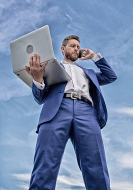 Her zaman temas halinde. Beceri iletişim. Adam resmi takım modern teknoloji Yöneticisi girişimci cevap telefon görüşmesi. Adam iyi giyimli işadamı dizüstü speak telefon mavi gökyüzü arka planı süre tutan