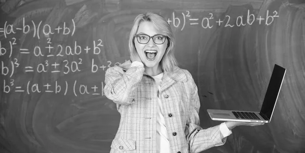 Education is fun. Woman teacher wear eyeglasses holds laptop surfing internet. Digital technologies concept. Educator cheerful lady with modern laptop surfing internet chalkboard background — Stock Photo, Image