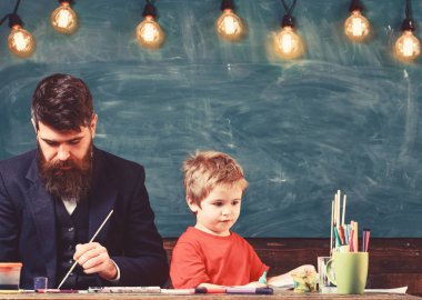Öğretmen ve çocuk sınıf kara tahta arka plan ile. Baba ve oğul birlikte içinde boyama çalışma odası. Aile meşgul yüzleri oluşturma, resim çizme