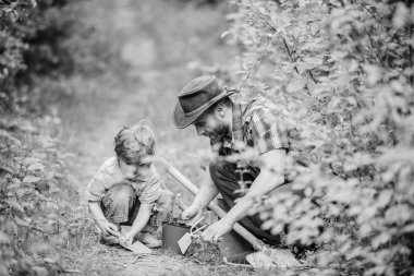 Bahçe araçları. Bahçe hobi. Babam küçük oğul bakım fabrikalarında ders veriyor. Bahar bahçe rutin. Çiçek dikmek. Bahçede küçük yardımcı. Çiftlik ailesi. Doğa arka planda küçük çocuk ve baba