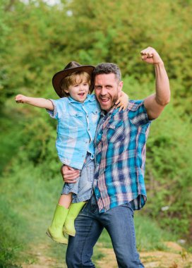 Güç babası. Çocuk eğlenceli kovboy baba sahip. Rustik bir aile. Sevimli kovboy büyüyor. Bahçede küçük yardımcı. Küçük çocuk ve baba doğada arka planda. Maceraların ruhu. Baba gibi güçlü