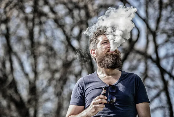 Nubes blancas de humo aromatizado. Fumar cigarrillo electrónico. Hombre barba larga relajado con hábito de fumar. El hombre con barba y bigote exhala humo. Concepto de alivio del estrés. Barbudo hombre fumar vapor —  Fotos de Stock