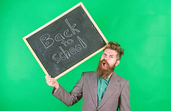 Professeur barbu homme tient tableau noir avec inscription retour à l'école fond vert. Continue de travailler. Professeur avec les cheveux ébouriffés stressant au sujet de l'année scolaire commence. Enseigner une profession stressante — Photo