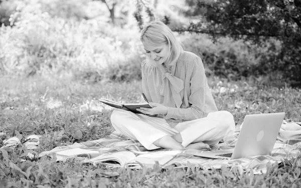 Kvinna med laptop sitta på matta gräs äng. Flicka med anteckningsblock skriva lapp. Frilansande karriärkoncept. Guide börjar frilansa karriär. Frilansarbete utomhus. Bli framgångsrik frilansare — Stockfoto
