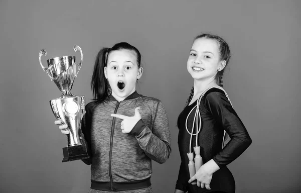 当然の賞だ女の子の運動の子供たちは勝利を祝う。金色のゴブレットを持つ運動の女の子。チャンピオンシップに勝つ。私たちのチームは1位です。子供の体操選手運動キッズ幸せなチャンピオン。スポーツの成果 — ストック写真