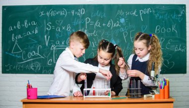 Renkli sıvı maddelerle test tüpleri. Sıvı durumları inceleyin. Test tüplü grup öğrencileri kimyasal sıvılar üzerinde çalışıyorlar. Okul laboratuarı. Kızlar ve erkek sıvı deneyi yapıyorlar.