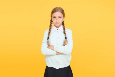 Sarı arka plandaki akıllı küçük kız. Eğitim konsepti. Okula dönüyorum. Okul üniformalı mutsuz bir kız. Bilgi günü. çocukluk mutluluğu. Çocuk modası. Okul pazarı. Zeki ve kendinden emin öğrenci.