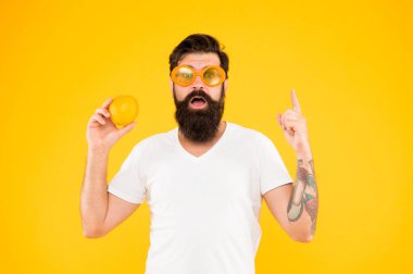Sağlıklı portakal tarifi fikir. Hipster'ın deha fikri sarı arka planda parmağını yukarı yasladı. Sakallı adamın doğal beslenme konusunda parlak bir fikri var. Süper yemek fikri