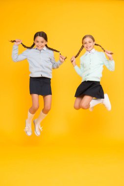 Bugün saç stilini güzelleştirmek. Sarı arka planda atlama uzun saç modeli ile sevimli küçük kızlar. Orta havada örgülü saç modeli tutan sevimli küçük çocuklar. Harika saç modeli her gün