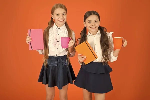 Energize your day. Cute schoolgirls holding cups and books. Little children drinking morning tea or milk. School children having breakfast in morning. Small girls enjoying their school breakfast — Stock Photo, Image