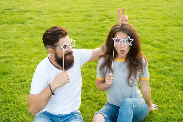 Being crazy in love. Sensual woman and bearded man in crazy mood relaxing on green grass. Crazy couple having fun with party props. Feeling playful and crazy