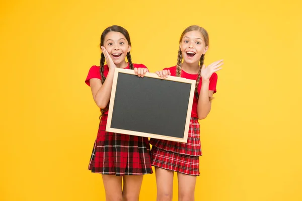 Quelle bonne nouvelle. les enfants présentant le tableau d'affichage. grosses ventes. heureuses petites filles avec tableau noir. endroit pour l'annonce. bureau d'information. présentation du projet scolaire. espace de copie — Photo