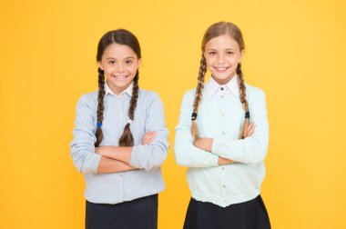 Birlikte çalışmak eğlenceli. sarı arka planda akıllı küçük kızlar. bilgi günü. mutlu çocukluk. çocuk moda. Dostluk ve kardeşliği. eğitim konsepti. geri okula. Okul üniformalı kızlar