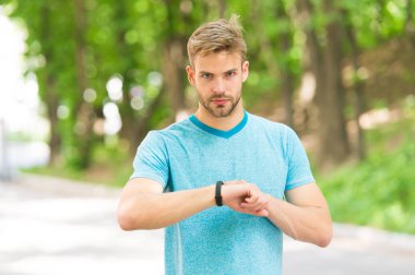 Akıllı saat ile Sportsman eğitimi. Fitness izci ayarlayın. Fitness koçu. Yararlı ayarlar. Bilek bandı Gadget 'ı. Atlet kontrol Fitness izci doğa arka plan. Atlet bak pedometre Gadget