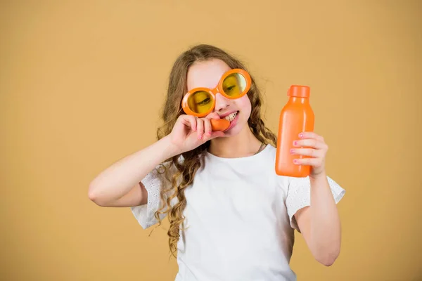 Μόδα παιδί γυαλιά ηλίου πίνουν αναζωογονητικό χυμό βιταμίνης. Υγειονομική περίθαλψη. Καλοκαιρινή δίαιτα βιταμινών. Καλή παιδική ηλικία. Φυσική πηγή βιταμινών. Κορίτσι τρώνε καρότο λαχανικών και πίνουν χυμό καρότο. Βιταμίνη διατροφή — Φωτογραφία Αρχείου