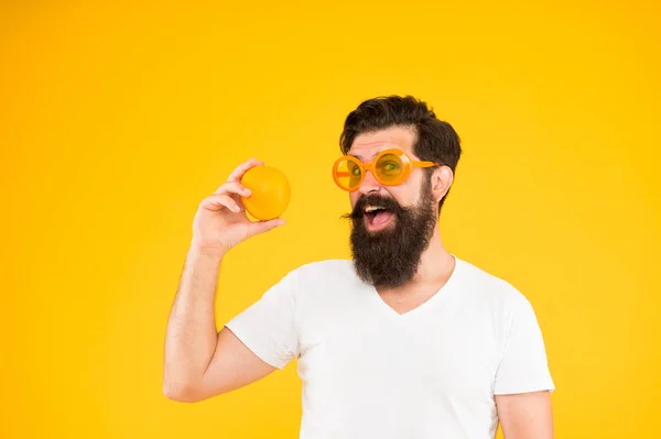 Летнее питание. Хипстер с бородой летом. Сочные фрукты. Человек бородатый хипстер в оранжевых солнцезащитных очках на желтом фоне. Веселый парень с спелыми фруктами. Летние каникулы. Свежий и здоровый — стоковое фото