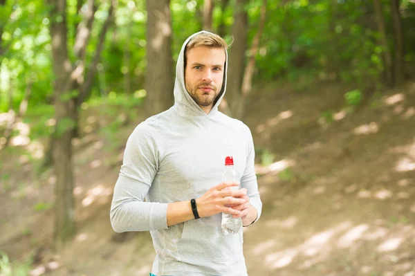 Relaxing after training. refreshing vitamin drink after workout. athletic man with water bottle. Athlete drink water after training. care body hydration. sport and health. man in hood drink water