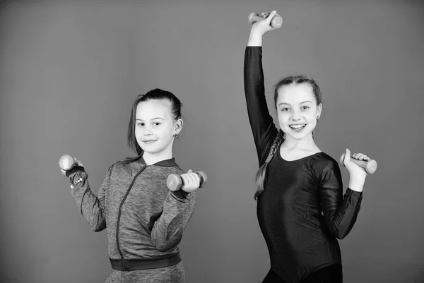 Principiante manubri esercizi. I bambini tengono i manubri sfondo blu. Sport per ragazzi. Facili esercizi con manubrio. Educazione sportiva. In cammino verso un corpo più forte. Ragazze che si esercitano con i manubri — Foto Stock