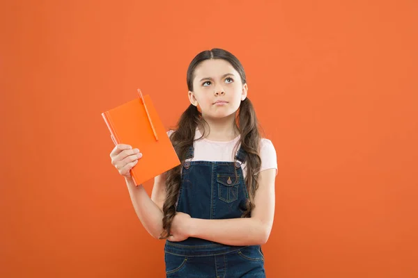 Schoolmeisje lezen boek op oranje achtergrond. notities schrijven. Kid Diary. poëzie en roman. modern onderwijs. denken klein meisje met notebook. literatuur les. terug naar school. Dagboek voor meisje concept — Stockfoto