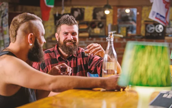 Friends relaxing in pub. Alcohol addiction. Men drunk relaxing at pub having fun. Hipster brutal man drinking alcohol with friend at bar counter. Men drinking alcohol together. Strong alcohol drinks