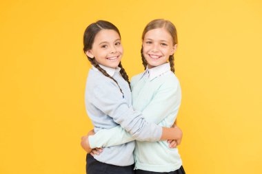 En iyi dostlar. sarı arka planda akıllı küçük kızlar. eğitim konsepti. geri okula. bilgi günü. çocukluk mutluluğu. çocuk moda. Dostluk ve kardeşliği. Okul üniformalı mutlu kızlar
