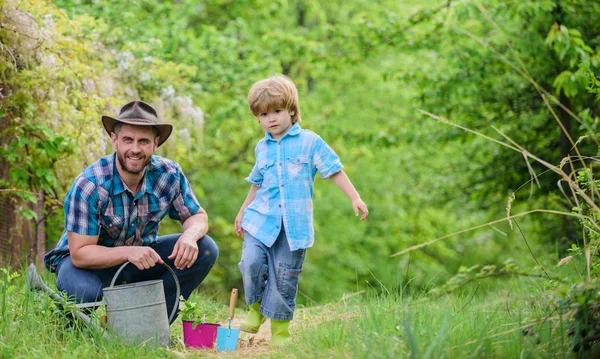 happy earth day. Family tree nursering. Eco farm. small boy child help father in farming. watering can, pot and hoe. Garden equipment. father and son in cowboy hat on ranch. Joyful process