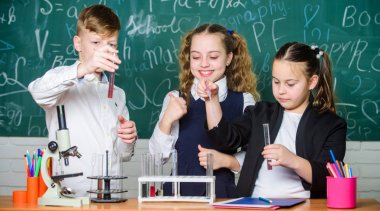 Okul laboratuvarı. Grup okulu öğrencileri Kimyasal sıvılar üzerinde çalışmadır. Kız ve çocuk öğrencisi sıvılarla okul deneyi yaparlar. Okul kimya dersi. Maddeler ile test tüpleri. Resmi eğitim