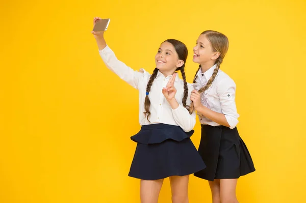 セフリ制服を着た小さな女の子学校に戻る教育ブログ。デジタル技術。オンライン教育。知識の日。スマートフォンで幸せな友人。子供たちは自分撮り写真、友情を作ります — ストック写真