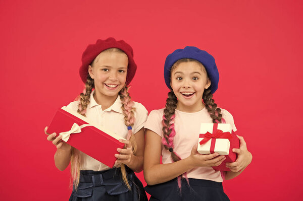 Маленькие симпатичные девочки получили праздничные подарки. Приносите счастье детям. Лучшие подарки для детей. Дети маленькие девочки в школьной форме и береты держат подарочные коробки. Дети в восторге от распаковки подарков
