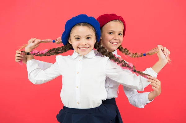 Glückliche Kindheit. Nette Kinder auf rosa Hintergrund. Kleine Kinder mit geflochtenen Haaren in langen Zöpfen. Kleine Kinder in Schuluniform und Baskenmützen. Entzückende Schulkinder mit Mode-Look — Stockfoto