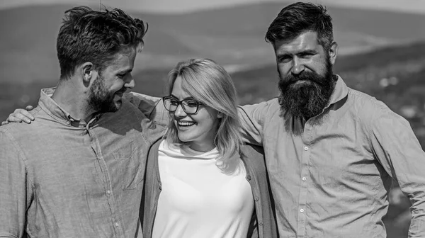 Gesellschaft von drei glücklichen Kollegen oder Partnern umarmt Outdoor, Natur Hintergrund. Männer mit Bart im Hemd und Blondine mit Brille als erfolgreiches Team. Business-Team-Konzept. Unternehmen an der Spitze — Stockfoto