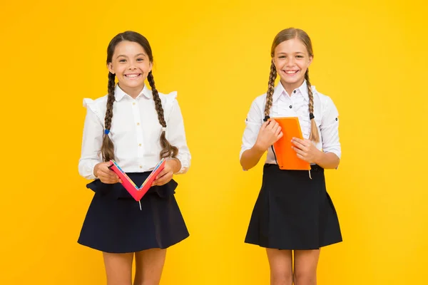 Las colegialas estudian juntas sobre fondo amarillo. Estudia lenguaje. Los niños lindos estudian con el libro de texto. Practicar y mejorar las habilidades de lectura para estudios escolares. De vuelta al concepto escolar. Las niñas tienen libro — Foto de Stock