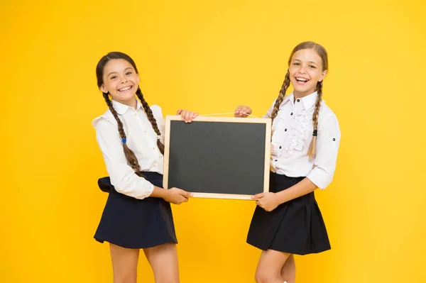 Κοίτα εδώ. Σχολείο κορίτσια χαριτωμένες κόρες κρατούν μαυροπίνακα αντίγραφο χώρου. Σχέδιο ανακοίνωσης του σχολείου. Οι συμμαθητές μας έχουν κίτρινο φόντο. Γίνε μέλος της σχολικής λέσχης. Η Κοινότητα των μαθητών. Σχολικό πρόγραμμα — Φωτογραφία Αρχείου