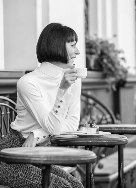 Gourmet concept. She loves sweets. Woman attractive elegant brunette eat gourmet cake cafe terrace background. Pleasant time and relaxation. Delicious gourmet cake. Girl relax cafe with cake dessert