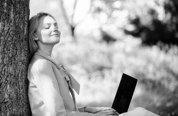 Flicka arbete med laptop i park sitta på gräset. Naturliga miljön office. Arbeta utomhus fördelar. Kvinna med laptop arbete utomhus lean träd. Minut för att slappna av. Utbildning teknik och internet koncept — Stockfoto